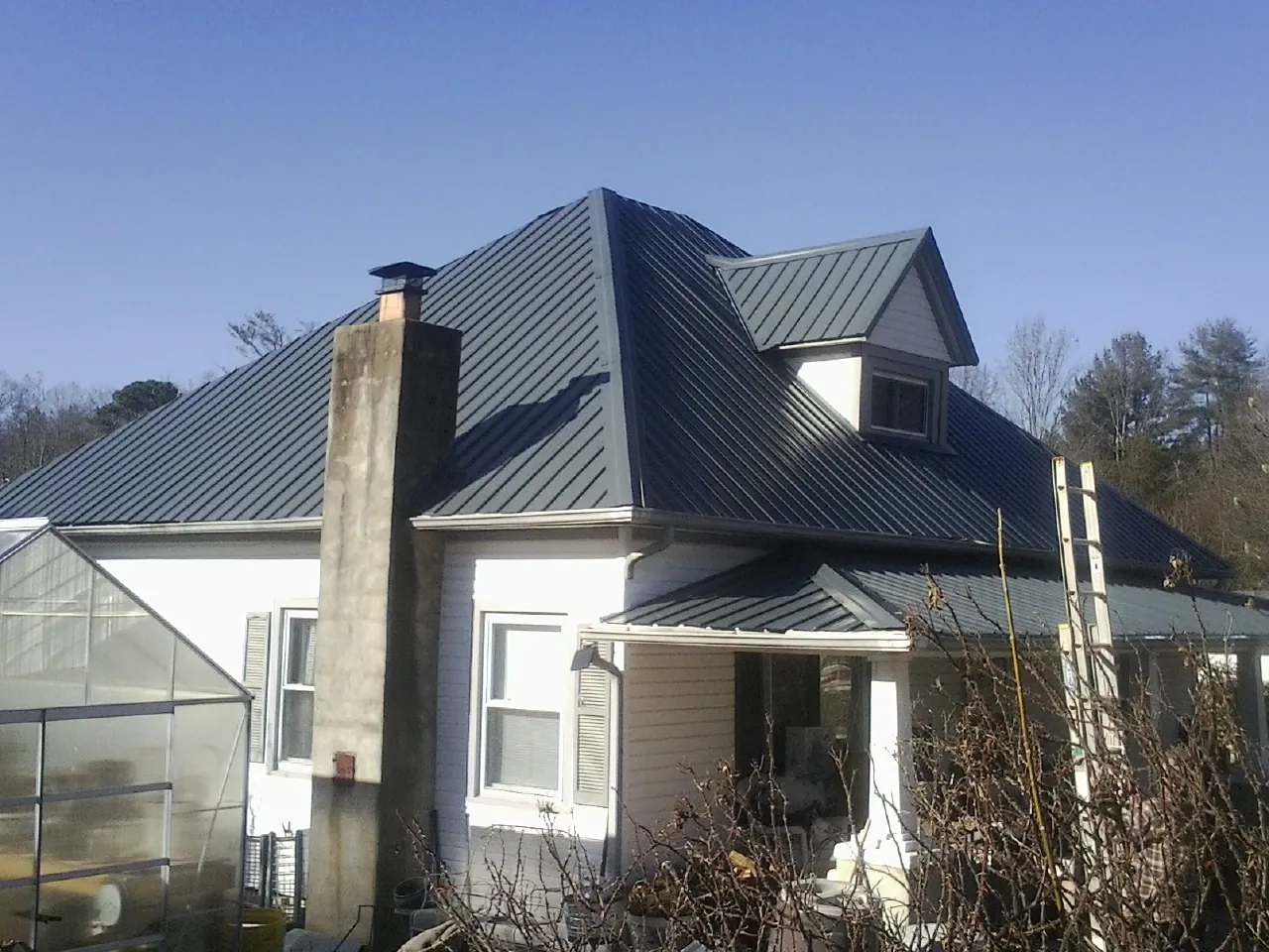 Dark blue standing seam metal roof on a white farmhouse with dormer — Slate & Tile Roof Repair by Roofing Brothers in Culleoka