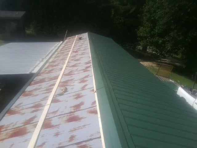 Old rusted panels beside newly installed green metal roofing — Wind Damage Roof Repair by Roofing Brothers in Culleoka