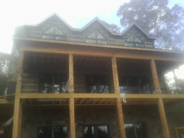 Dormers and porch framing on a large log home under construction — Roof Coating work by our crew in Culleoka