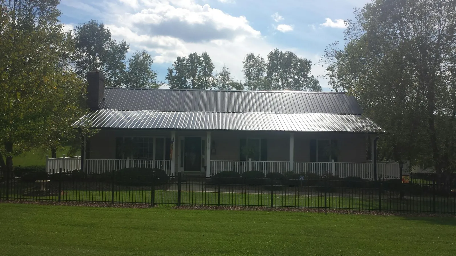 Gray metal roof on a brick ranch with a full width front porch — Gutter Guard Installation work by our crew in Culleoka