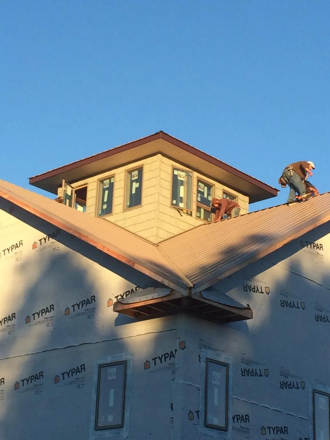 Roofers working around a rooftop cupola on a new metal roof at sunset — Roof Waterproofing in Culleoka by Roofing Brothers